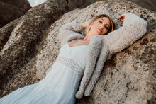 Load image into Gallery viewer, Model lying on giant boulder, sand & stone hedonistic cardi, straight arm sleeves, length of cardi to hips. Soft and oversized.
